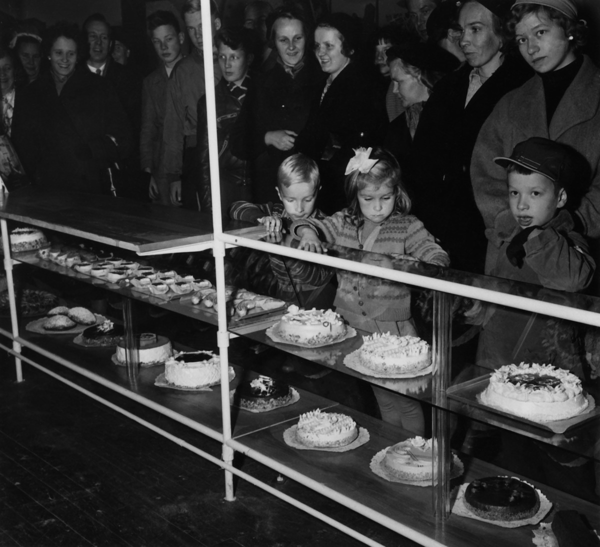 Ihmisiä katselemassa Elannon leipätehtaan kakkuja ja leivoksia