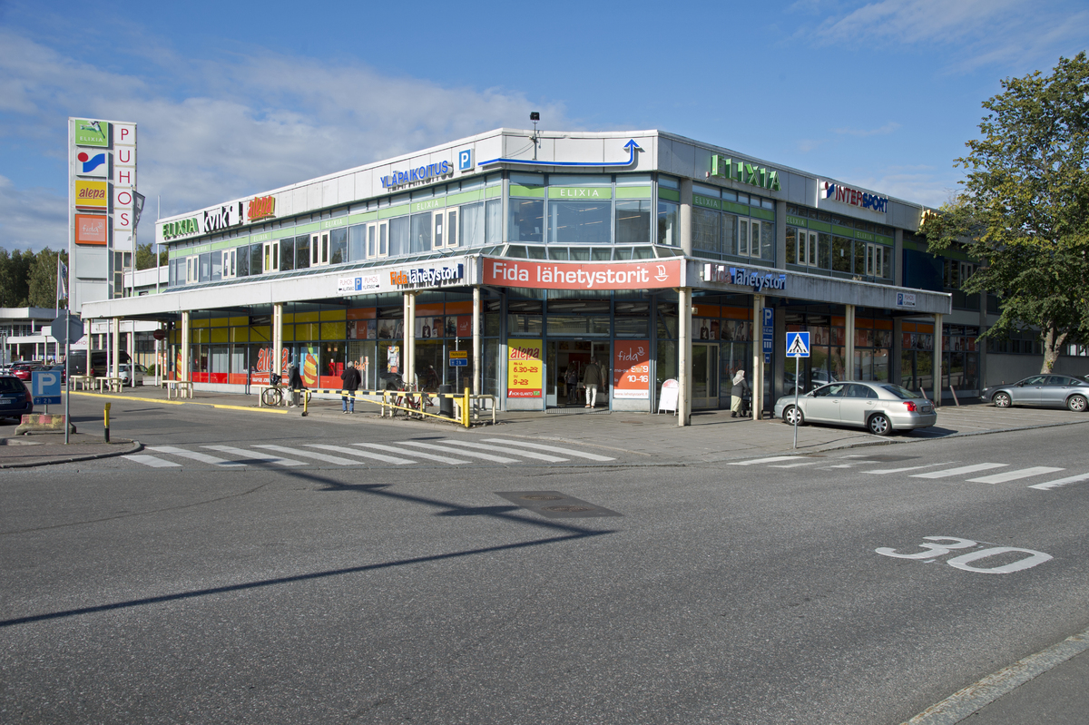 Puotinharjun ostoskeskus Puhos, Kastelholmantie 2. Valokuvassa näkyy ostoskeskuksen laajennusosa, joka tuli käyttöön 1980-luvun lopulla, Korhsholmantie 2. Valokuva on otettu kohdasta, jossa Korsholmantie liittyy Turunlinnantiehen