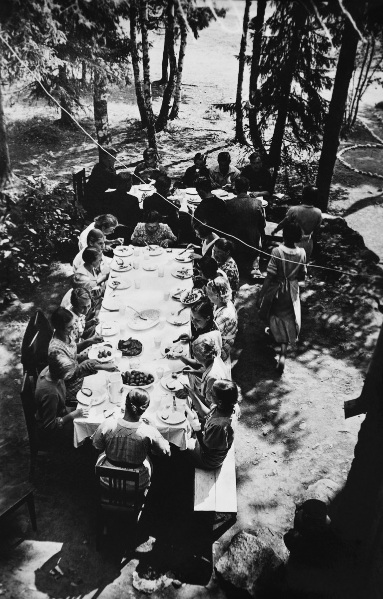 Sörnäisten nuorisoa ruokailemassa ulkona pöytien ääressä kesäkodilla Herttoniemessä (Herttuaniemessä)