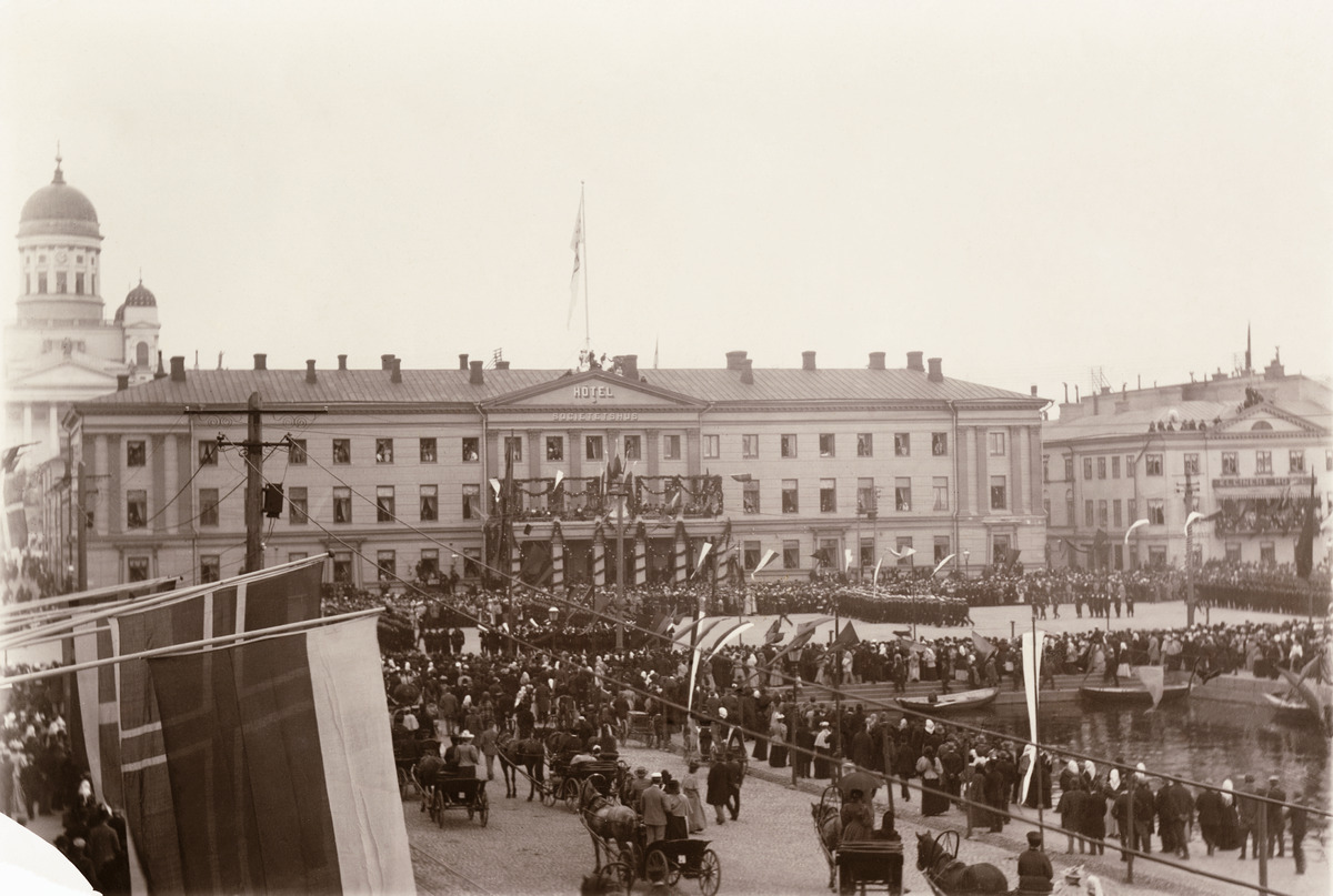 Paraati Kauppatorilla keisari Nikolai II:n kruunajaisten johdosta, taustalla juhlakoristeltu Hotelli Seurahuone (ruots