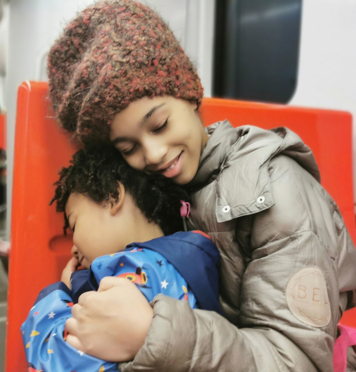 Sisarukset metrossa Helsingissä, kuvassa sisko halaa veljeä