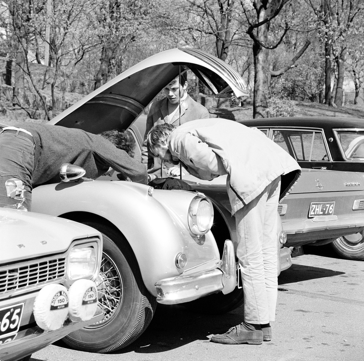 Nuoret miehet tarkistavat auton moottoria Kaivopuistossa