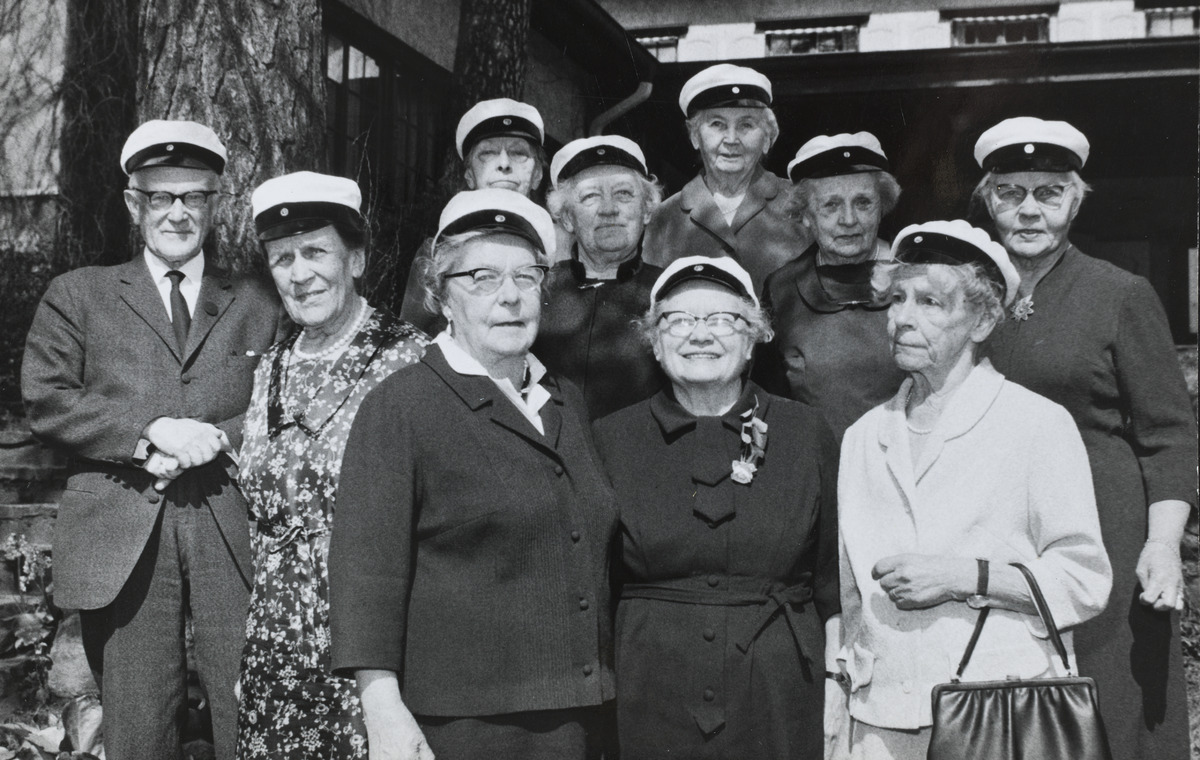 Helsingin Uuden Yhteiskoulun ylioppilaita vuodelta 1908 ryhmäkuvassa ylioppilaslakkeineen kuvattuna vuonna 1968