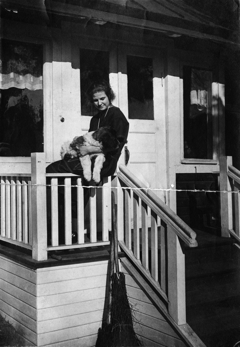 Greta Jakobsson Dicken-koiran kanssa kotinsa kuistilla Haagassa, nykyisen Eliel Saarisentien suunnilla