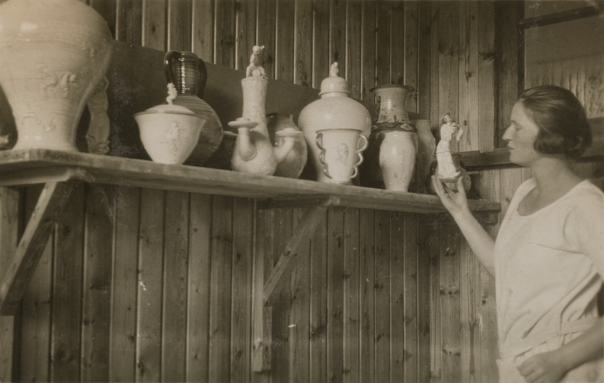 Keraamikko Friedl Holzer-Kjellberg tarkastelemassa tekemiään keramiikka-astioita Arabian tehtaalla