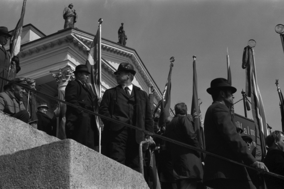 Ihmisiä lippuineen Tuomiokirkon portailla työväen vappujuhlassa 1