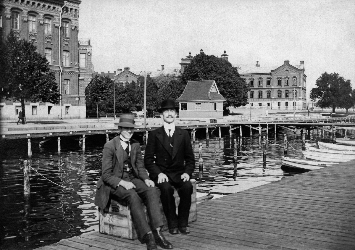 Kaksi miestä istuvat Pohjoisrannassa venelaiturilla